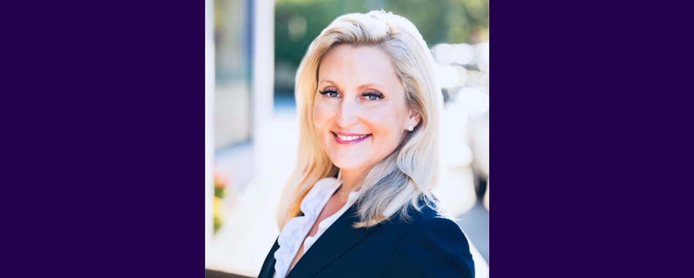 Heahshot of Emily Morris smiling at the camera with a dark purple background on the sides of the image.