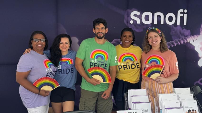 Sanofi employees participating in Pride Parade, wearing company-branded clothing and carrying educational materials about atopic dermatitis and asthma clinical trials.