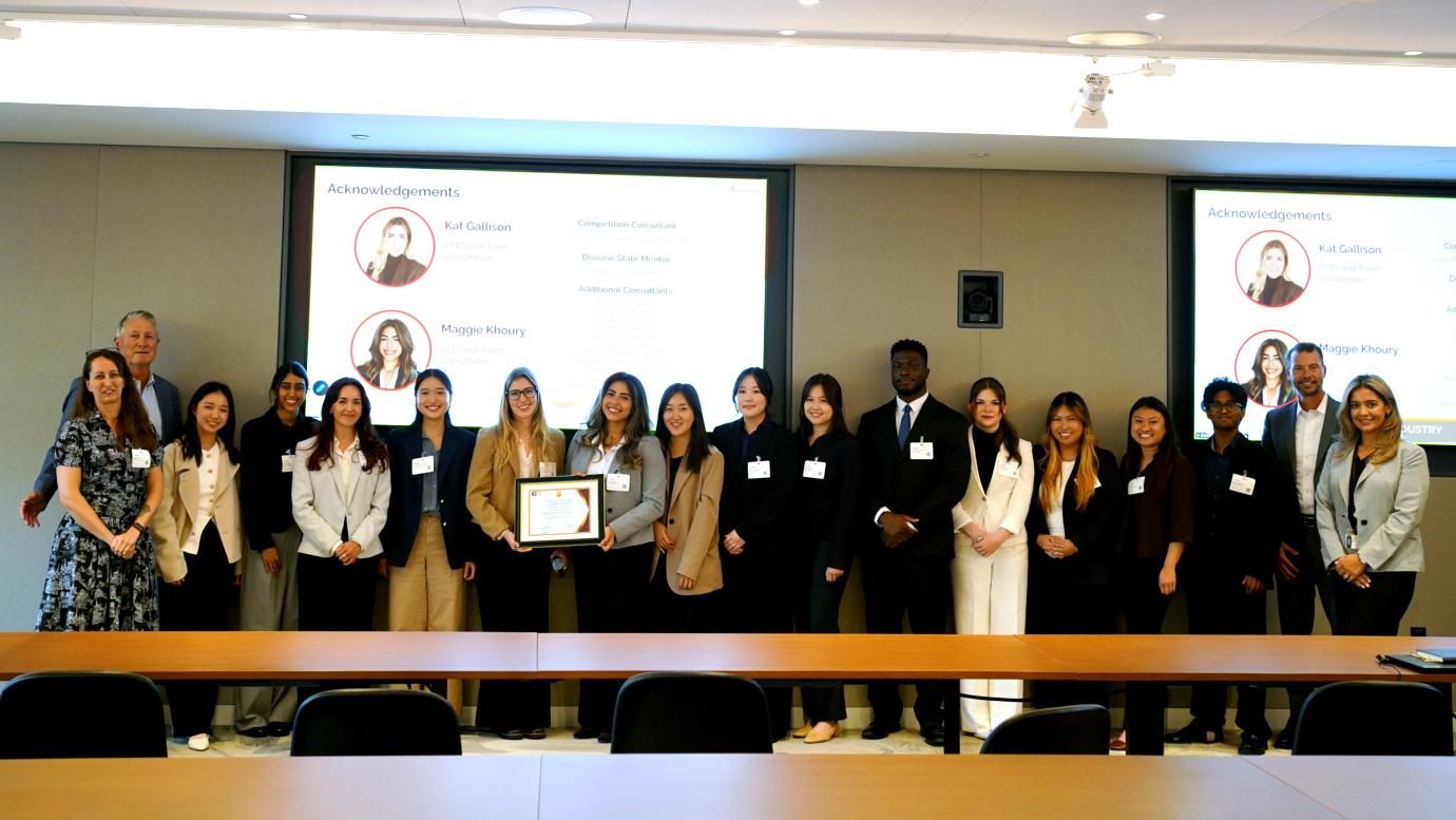 Pharmacy students and Sanofi representatives celebrate at the IPhO VIP Case Competition awards ceremony, standing together as an Acknowledgements slide honoring the competition's organizers plays on screen.
