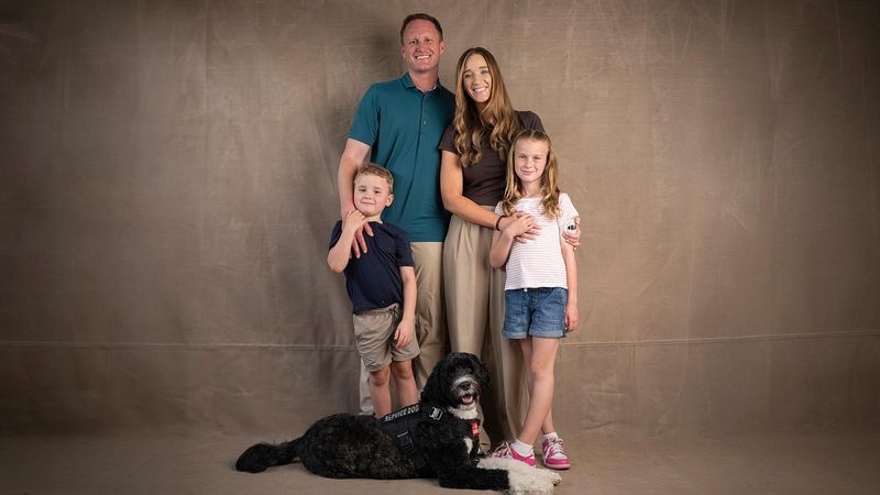 Family of four with service dog posing for portrait photo - parents with two children including daughter with type 1 diabetes