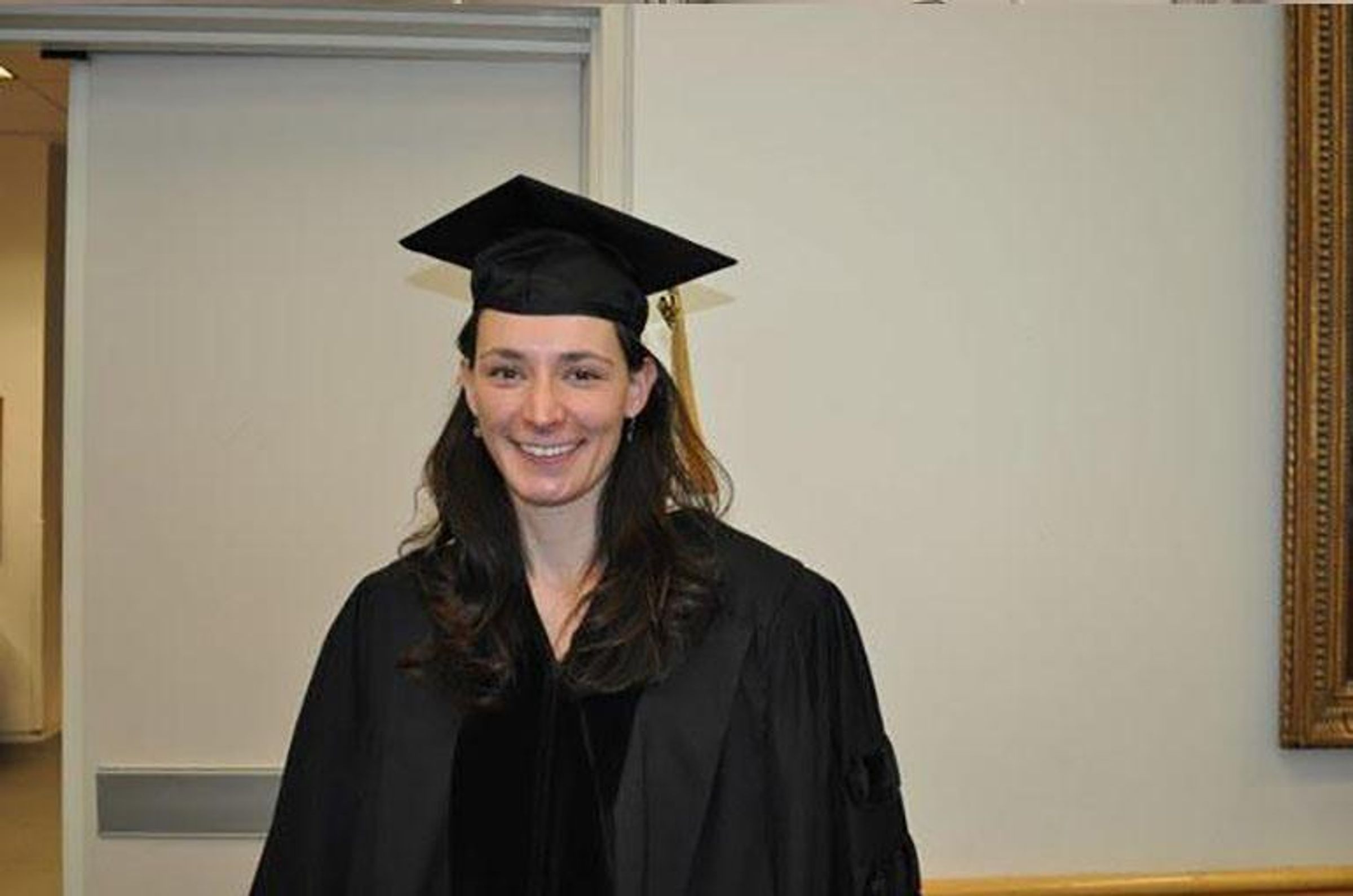 Dr. Kelly George wears a cap and gown at her PhD graduation.