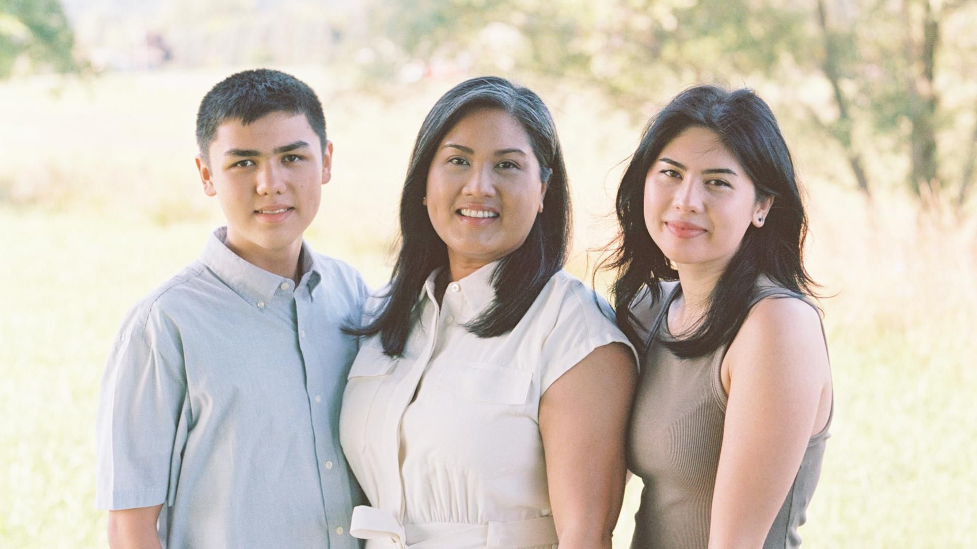 Chenda Cupak, along with her son and her daughter stand together in a field for a family portrait