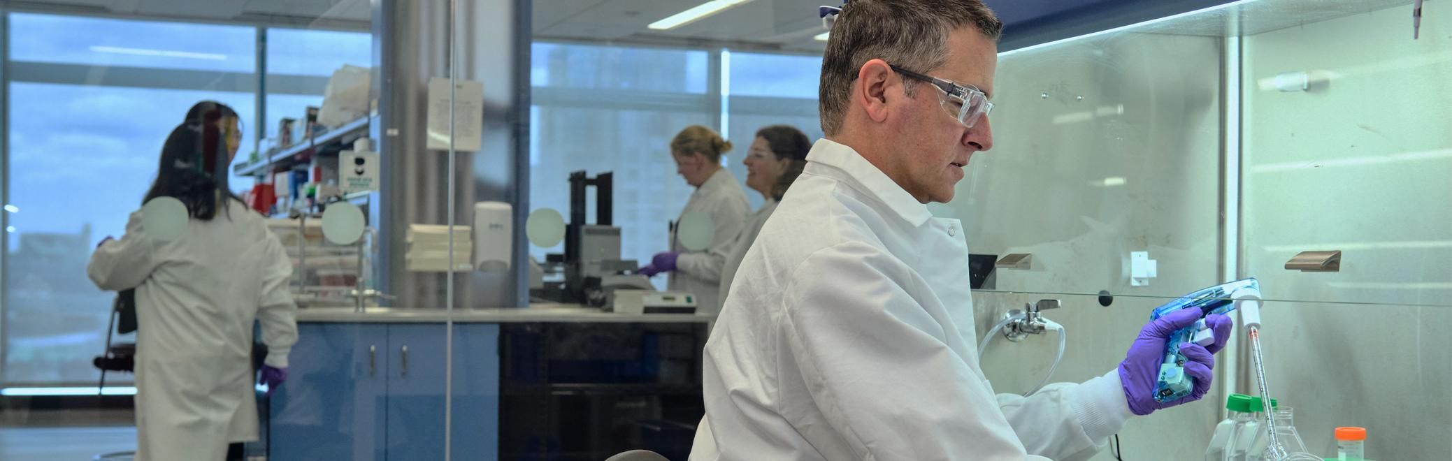 Stephane Poirier in lab gear testing samples at his lab. 