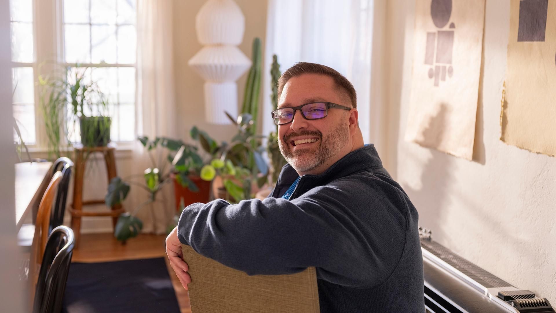 Steve, living with type 1 diabetes, smiling in a bright, plant-filled room — someone who lives fully with type 1 diabetes rather than being limited by it