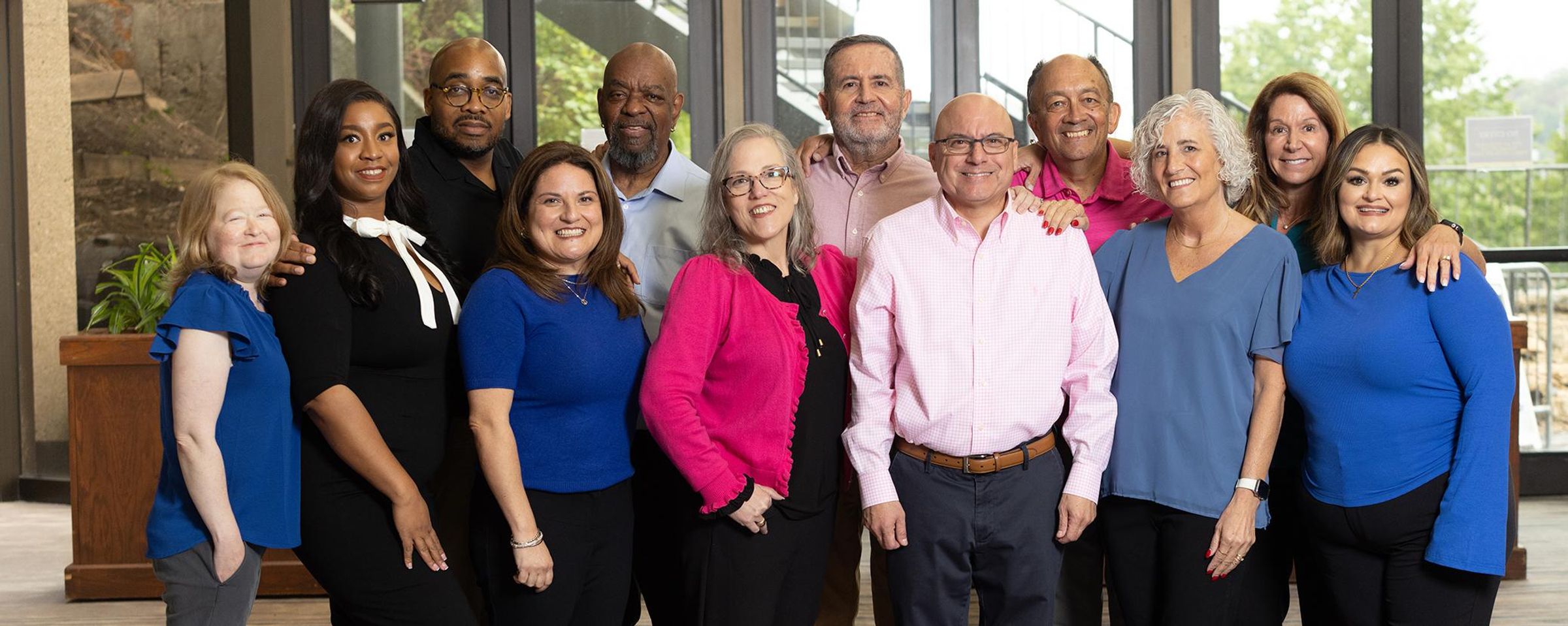 Nine proud participants of the Kidney Transplant Connectors (KTC) Program pose together in two rows in a hallway, smiling at the camera. They come together, embodying hope, community, and the power of connection in the transplant journey.