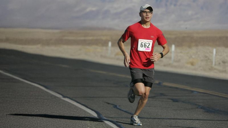 Patient living with Hemophilia A running a half marathon on a desert road. He is wearing a red t-shirt and dark grey shorts and has the race number 662 on his shirt front.