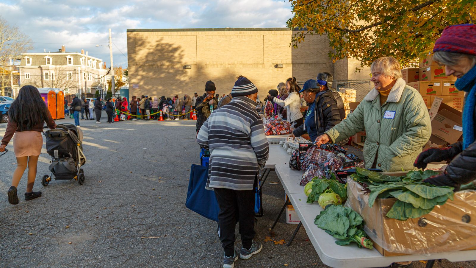 Healthy Waltham volunteers distribute fresh produce to community members at an outdoor food distribution event.