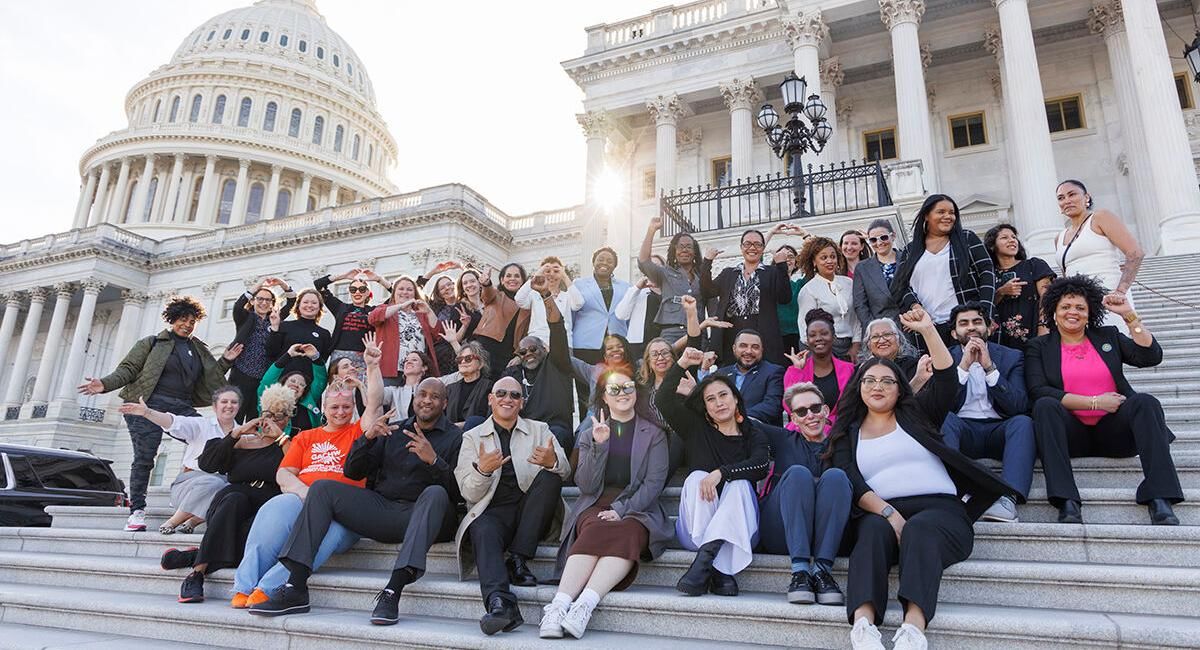 A large group of people sit on the steps of the Capitol in Washington DC