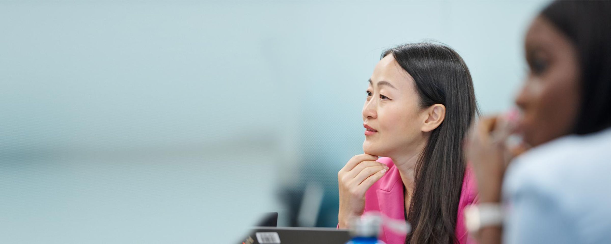 Asian woman in background and woman in foreground during a Sanofi inclusion workshop, listening attentively