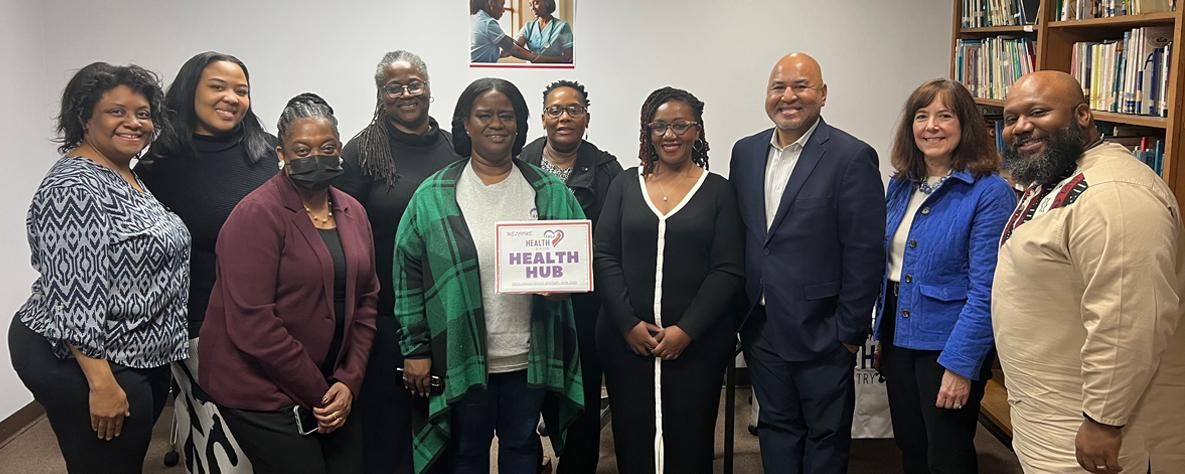 Two Sanofi employees visit H.E.A.L.U.S. Project Health Hub in Atlanta, Georgia, joining eight A.M.E. Zion Church Health Ministry members. Group poses with "Welcome to Health Hub" sign, celebrating Sanofi’s A Million Conversations community health partnership.