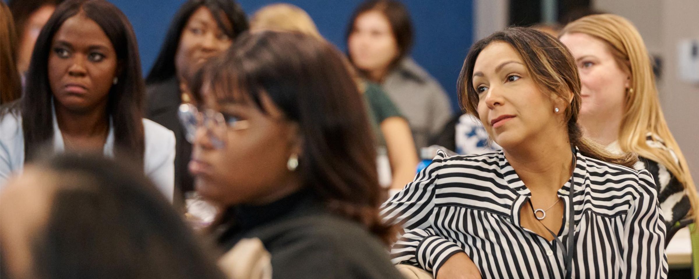 Group of women gathered in a conference room, engaged in conversation.