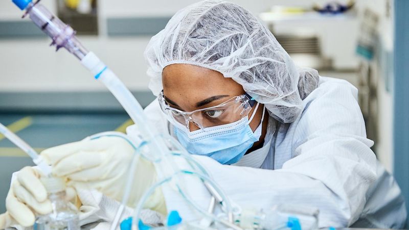 Sanofi employee in full protective equipment monitors sterile manufacturing equipment in a pharmaceutical production facility to ensure safe and reliable medicine production.